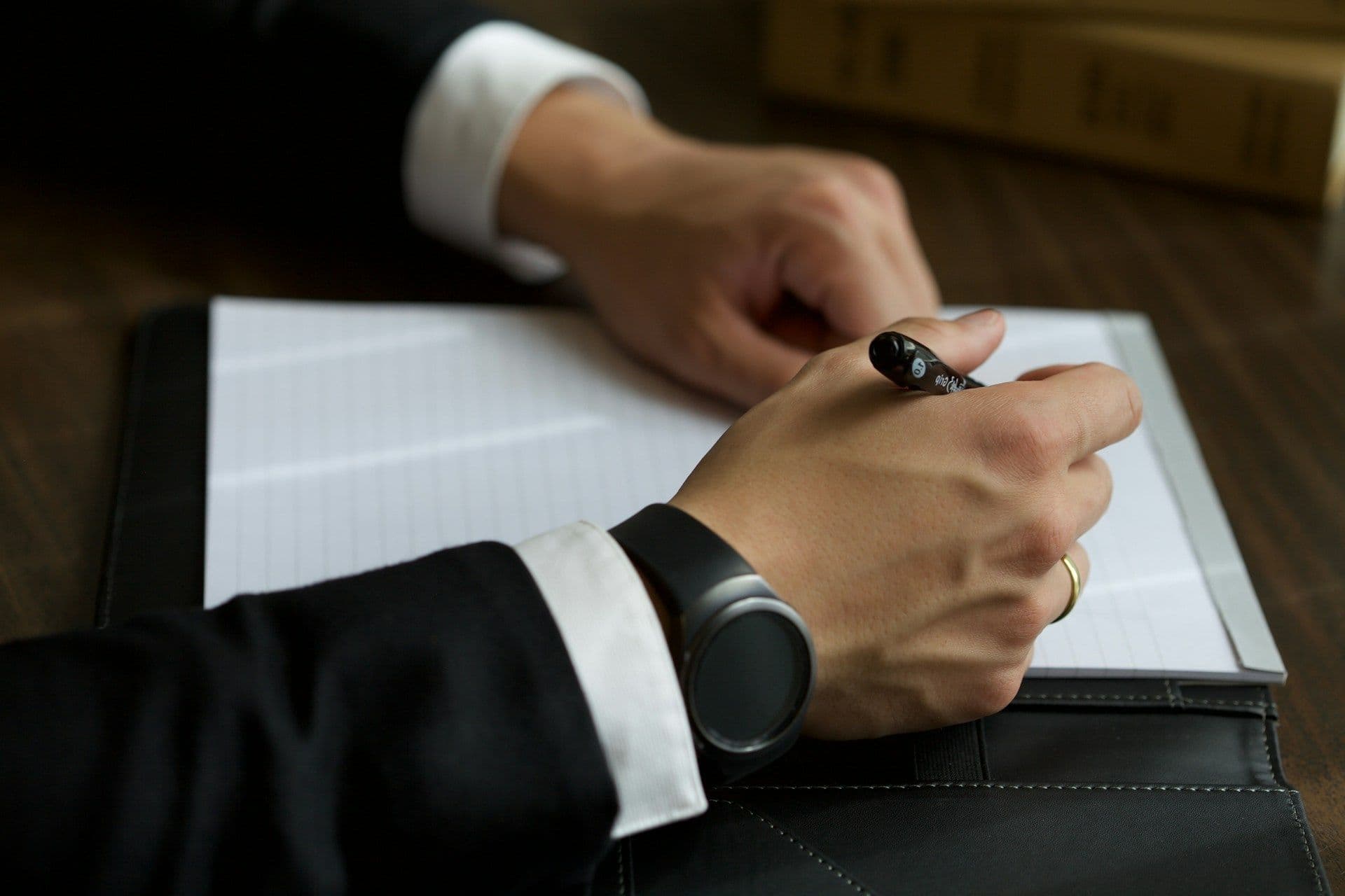 Lawyer writing notes and reviewing manual paperwork at a desk, representing traditional legal billing practices.